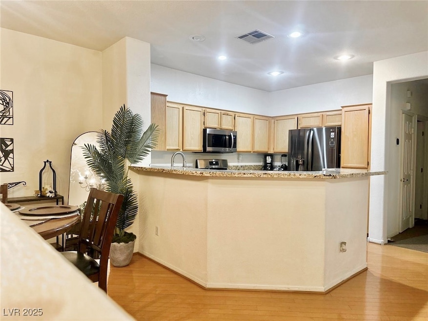 Kitchen with light brown cabinetry, light wood-sty