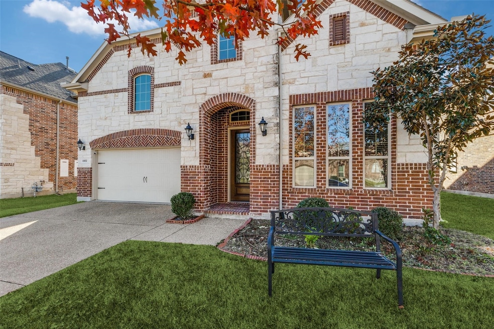 French provincial home with driveway, stone siding, a front yard, and an attached garage