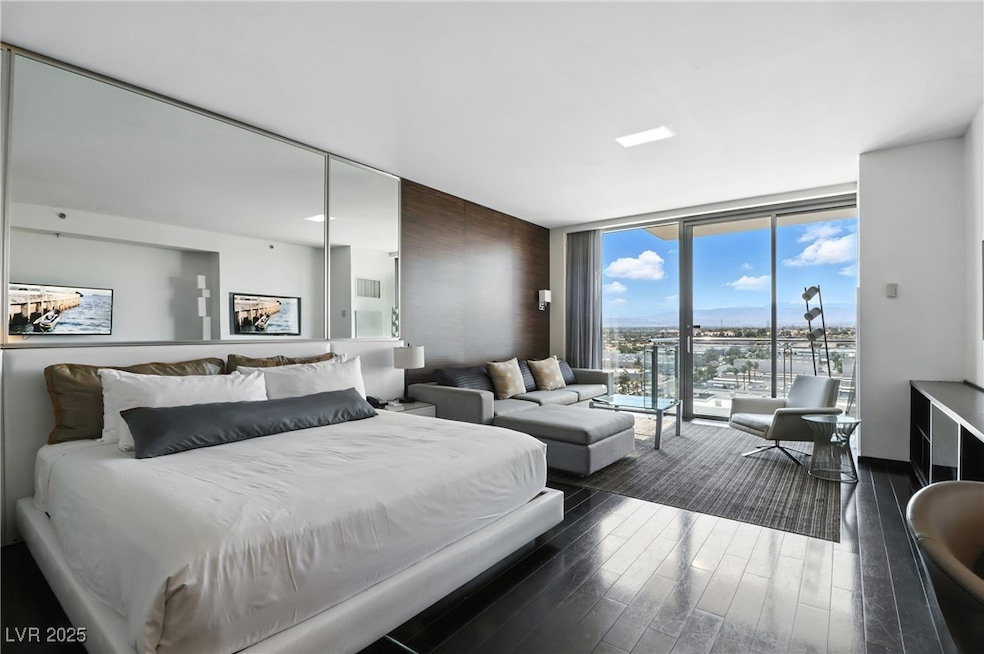 Bedroom with expansive windows, dark wood-style floors, and access to outside