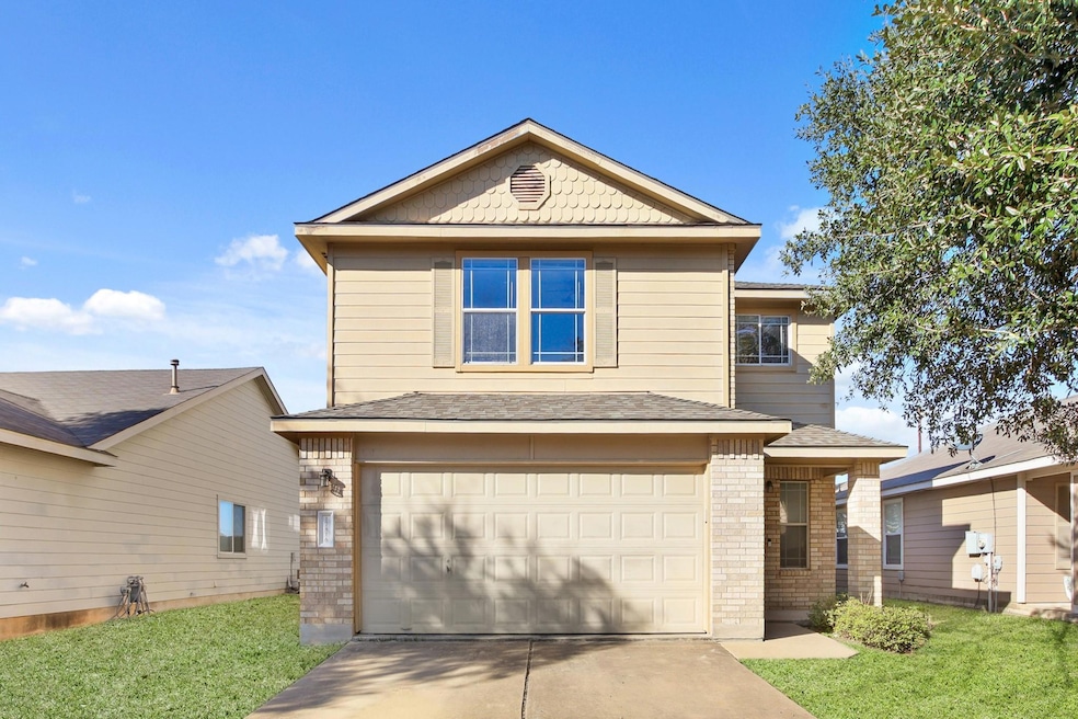 View of front facade featuring driveway, an attached garage, brick siding, a front lawn, and roof with shingles