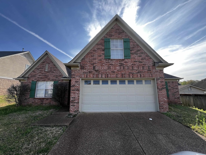 Traditional home with a garage, driveway, and bric