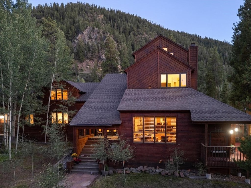 View of front of home with a view of trees, roof w