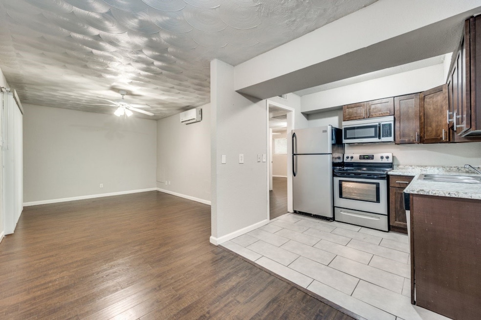 Kitchen with appliances with stainless steel finishes, dark brown cabinetry, a ceiling fan, light wood-type flooring, and open floor plan
