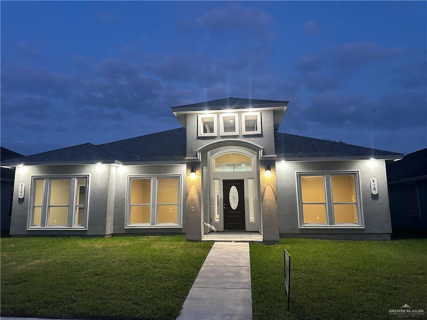 Doorway to property featuring a yard, stucco siding, and a shingled roof