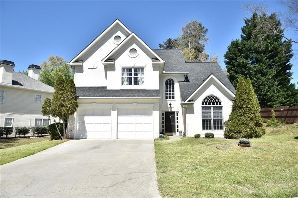 Traditional-style house featuring a garage, a shingled roof, concrete driveway, and stucco siding