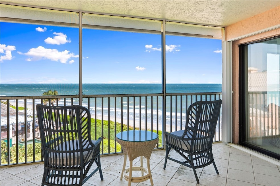 Sunroom / solarium with tile patterned floors and view of water and beach