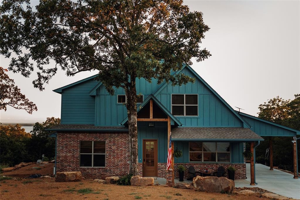 View of front of house featuring roof with shingles, board and batten siding, brick siding, and concrete driveway