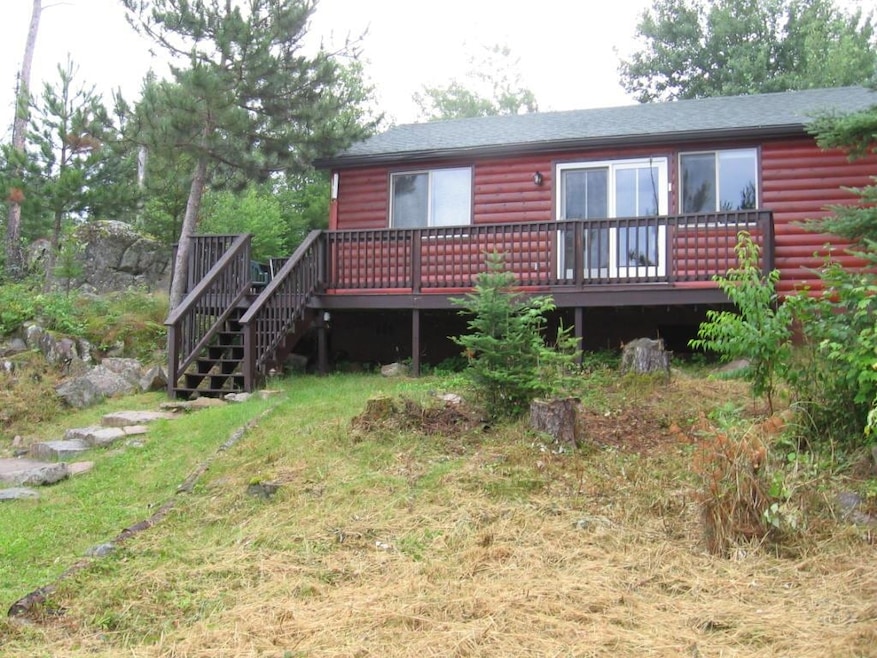 view of property with log veneer siding, a deck, stairs to dock