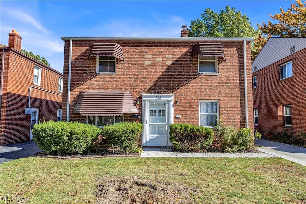 View of front facade with brick siding, a chimney, and a front yard