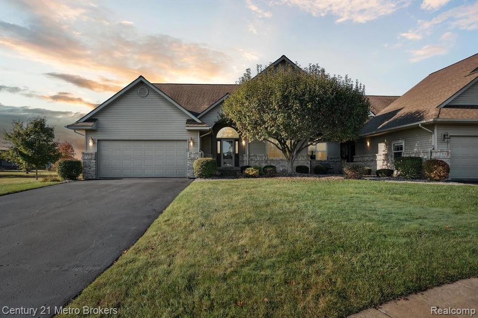 View of front of property with stone siding, a front lawn, driveway, and an attached garage