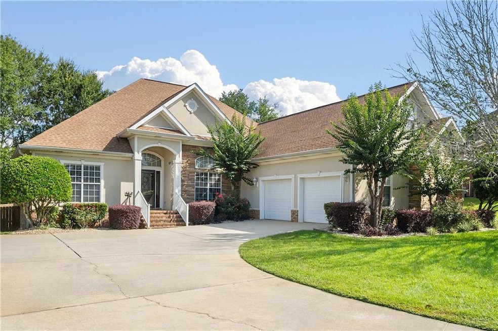 View of front of home with stucco siding, an attached garage, concrete driveway, a front yard, and stone siding