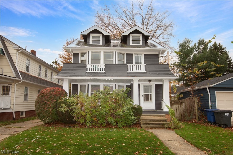 View of front of property with a balcony, a front lawn, and a garage
