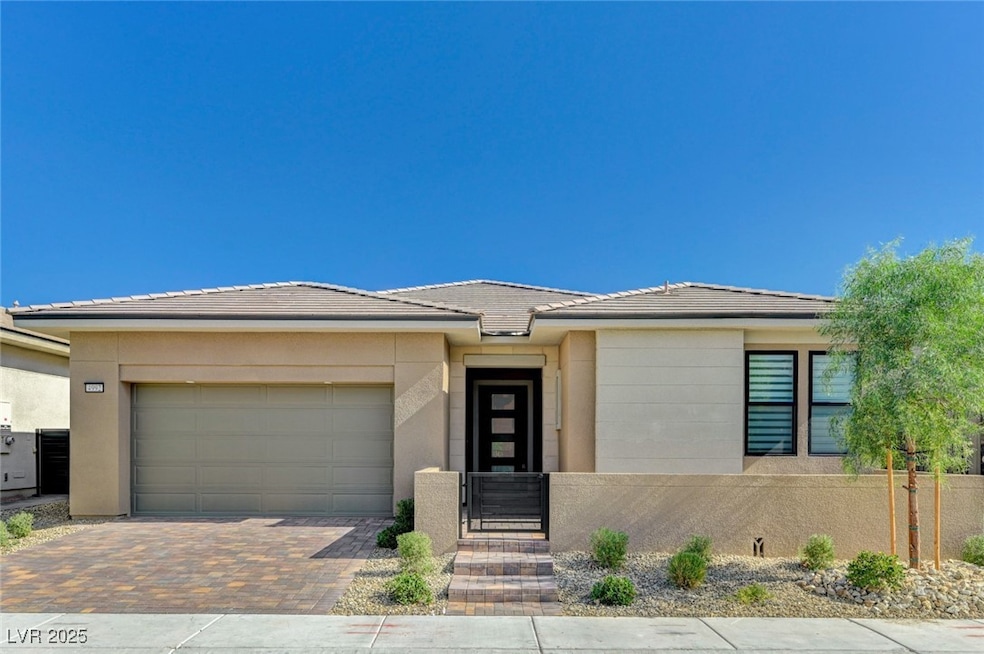 Prairie-style house with decorative driveway, a garage, a tiled roof, and stucco siding