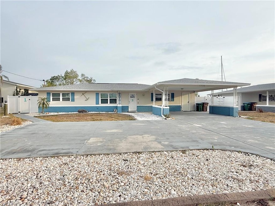 View of front facade featuring concrete driveway, a carport, stucco siding, and fence