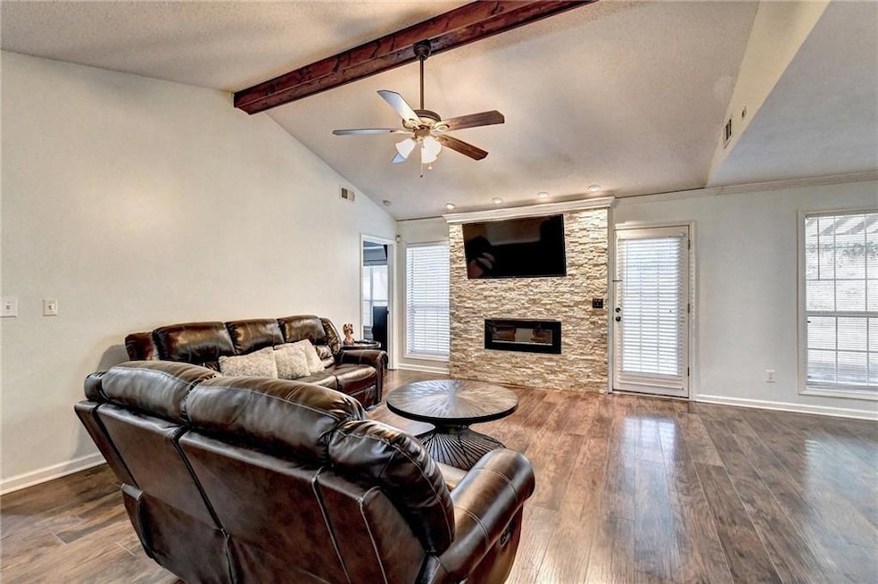 Living area with a ceiling fan, dark wood-type flooring, and a fireplace