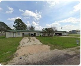 Ranch-style house with a front lawn, dirt drivewa