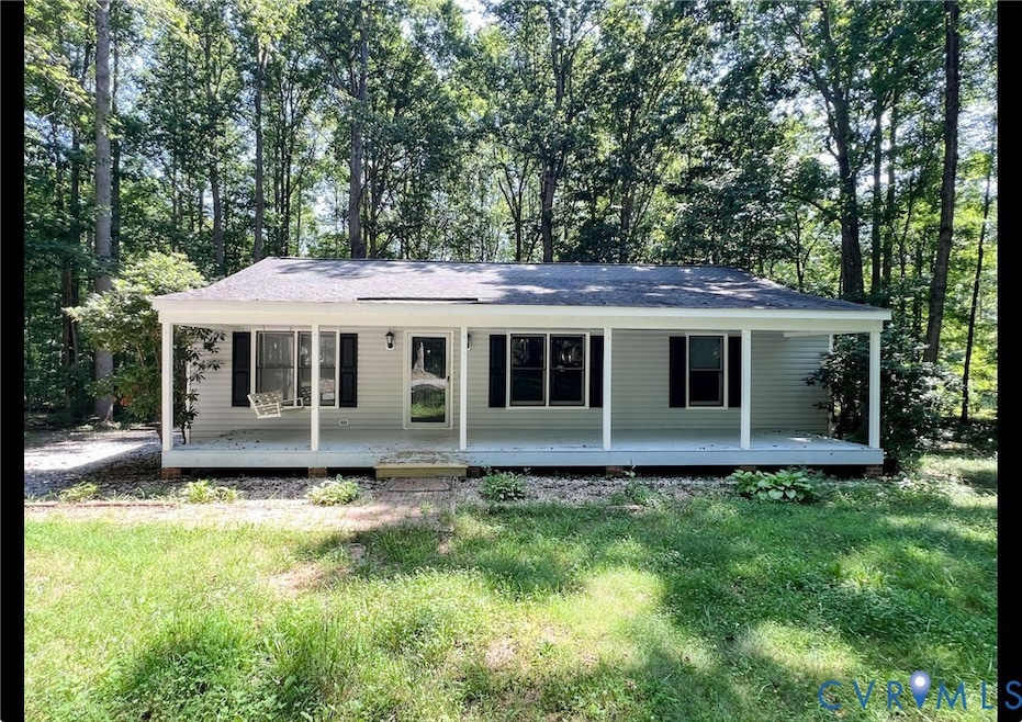View of front of property with a porch, a shingled roof, a front lawn, and view of scattered trees
