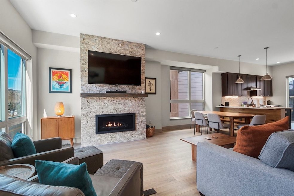 Living area featuring light wood-type flooring, a stone fireplace, and recessed lighting