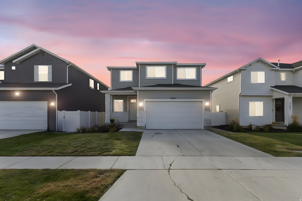 Traditional-style home with driveway, an attached garage, stone siding, and a gate