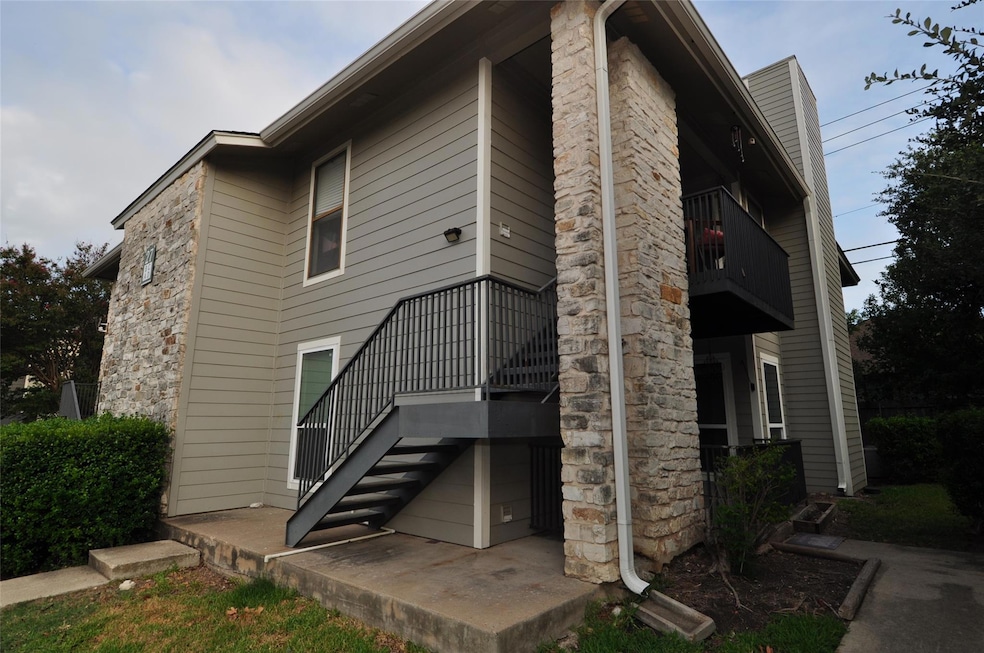 Back of house featuring a balcony and stone siding