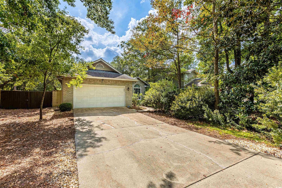 View of front of property with concrete driveway, an attached garage, fence, and brick siding