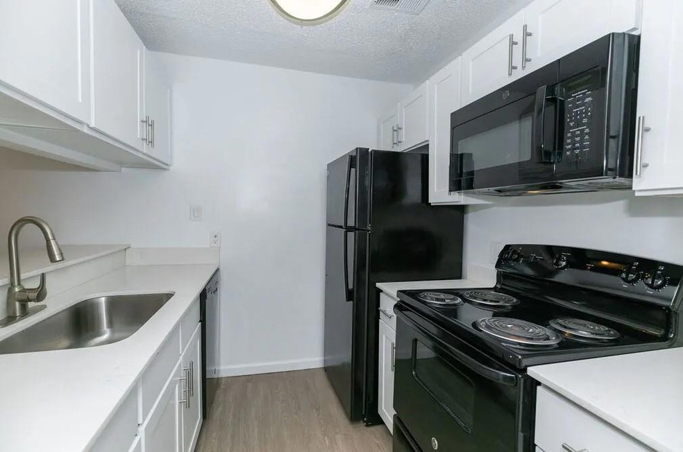 Kitchen with white cabinetry, black appliances, si