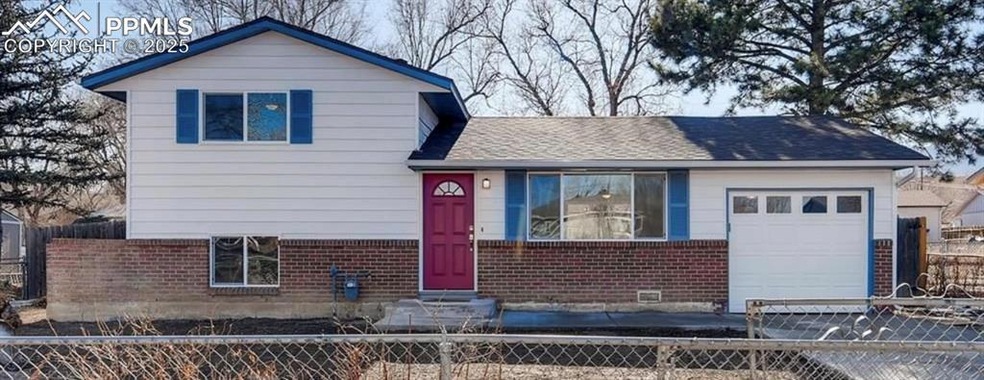 Split level home featuring a fenced front yard, brick siding, a garage, a shingled roof, and entry steps