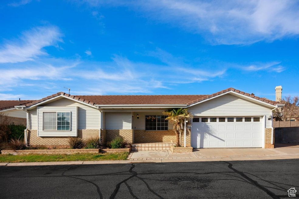 Single story home featuring brick siding, a garage, concrete driveway, and covered porch