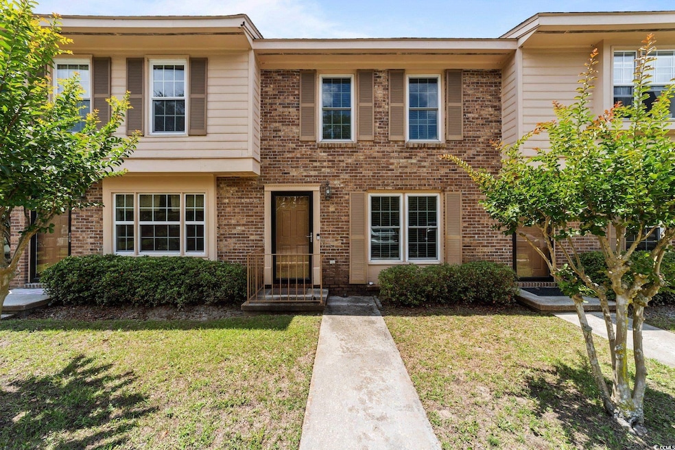 Multi unit property featuring a front yard and brick siding