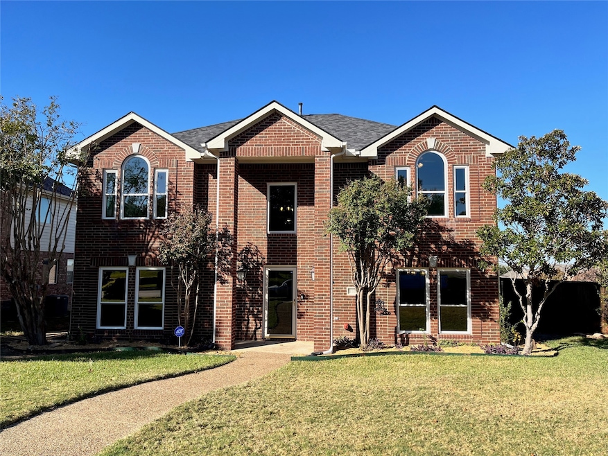 Traditional home with a front yard and brick siding