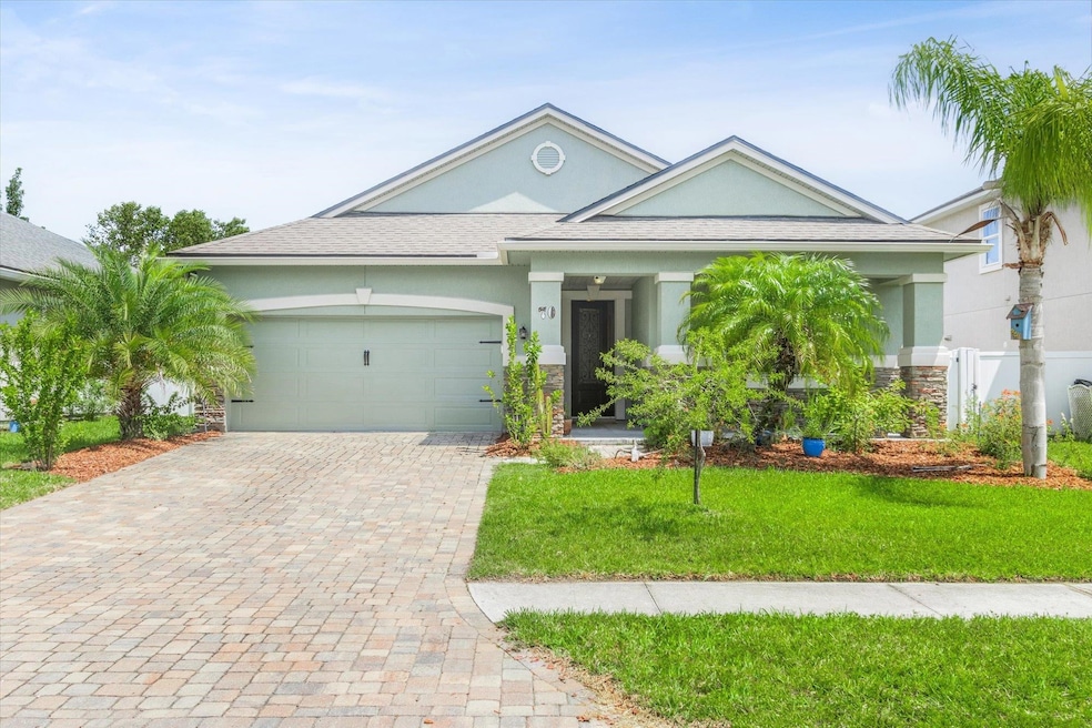 View of front of property featuring stucco siding, stone siding, a front yard, and decorative driveway