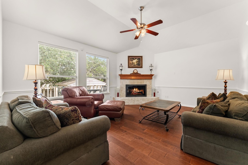 Living room featuring lofted ceiling, dark wood-style floors, a fireplace, and ceiling fan
