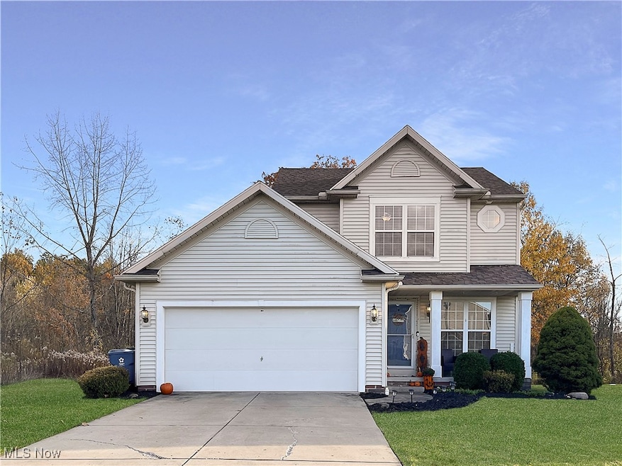 Traditional home with a front yard, concrete driveway, an attached garage, and a shingled roof