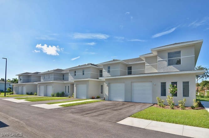 View of front facade with an attached garage, driv