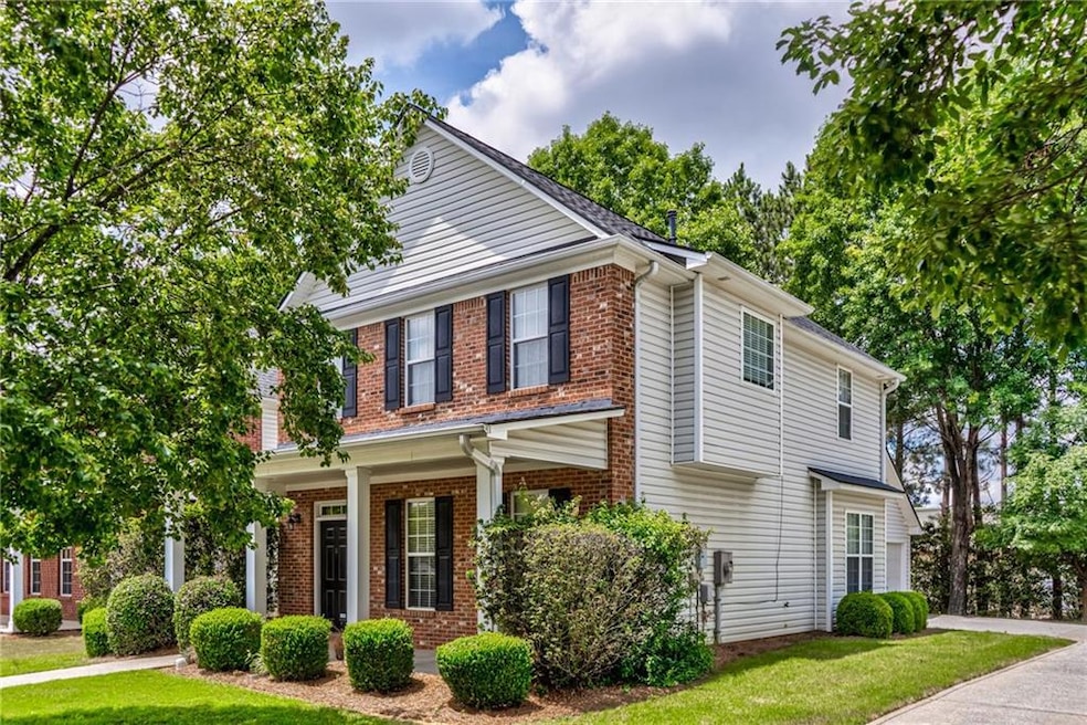 Traditional-style home featuring brick siding, a front yard, driveway, and a porch