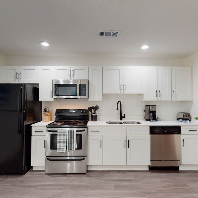 Kitchen with appliances with stainless steel finishes, white cabinetry, light wood-style flooring, and recessed lighting