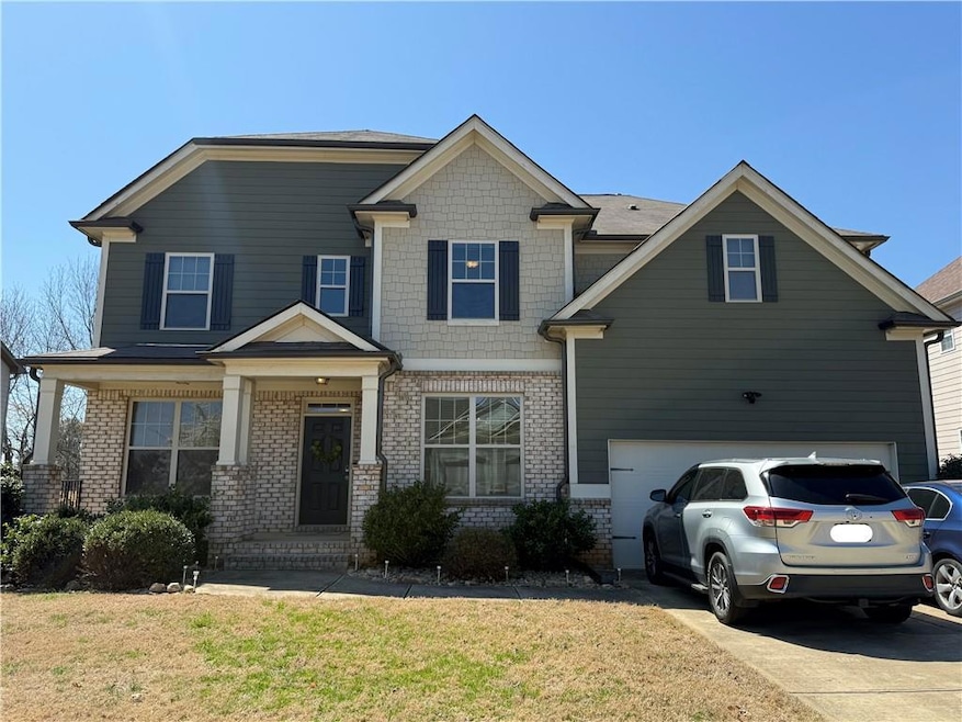 Craftsman-style home featuring driveway, brick sid