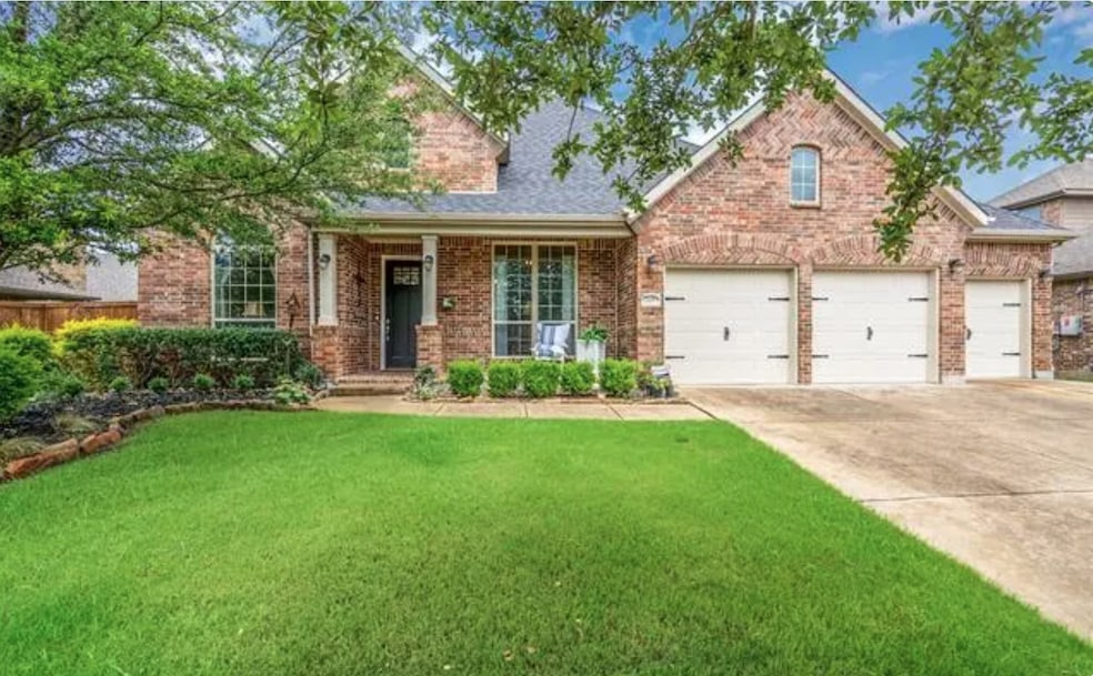 View of front of house with driveway, a porch, a front yard, a garage, and brick siding