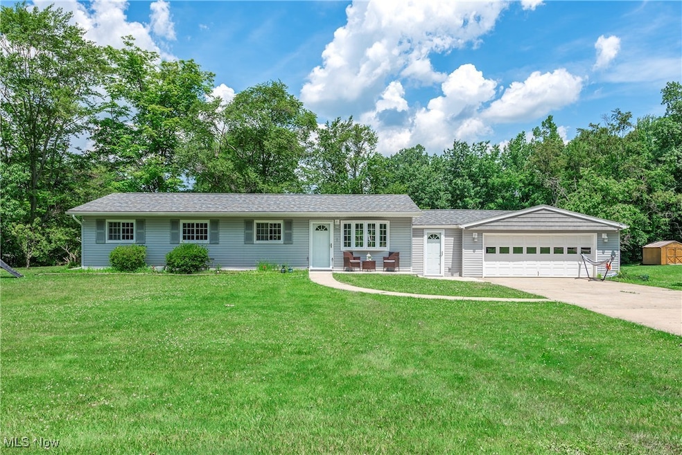 Ranch-style house featuring concrete driveway, an attached garage, and a front lawn