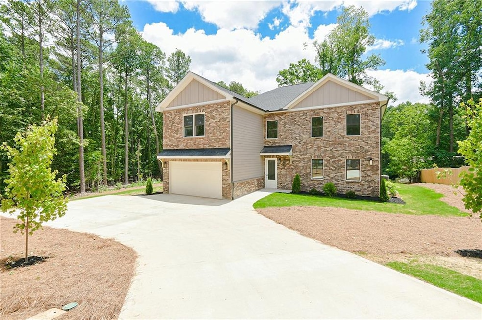 View of front of property featuring driveway, a garage, stone siding, board and batten siding, and brick siding