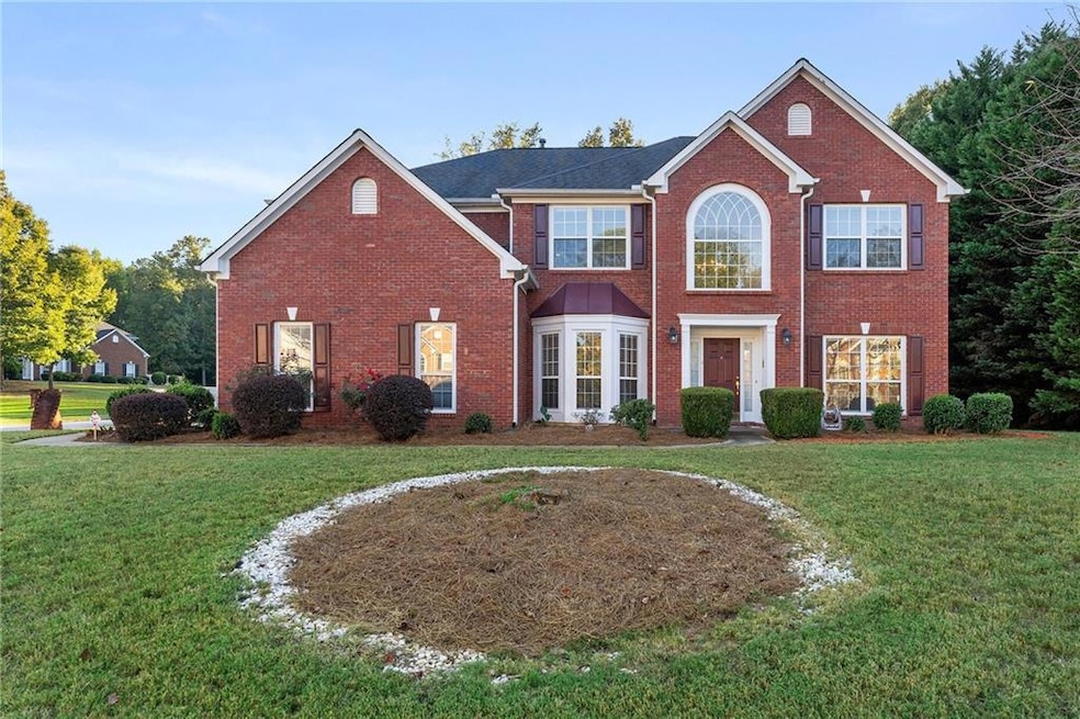 Colonial home with a front yard and brick siding