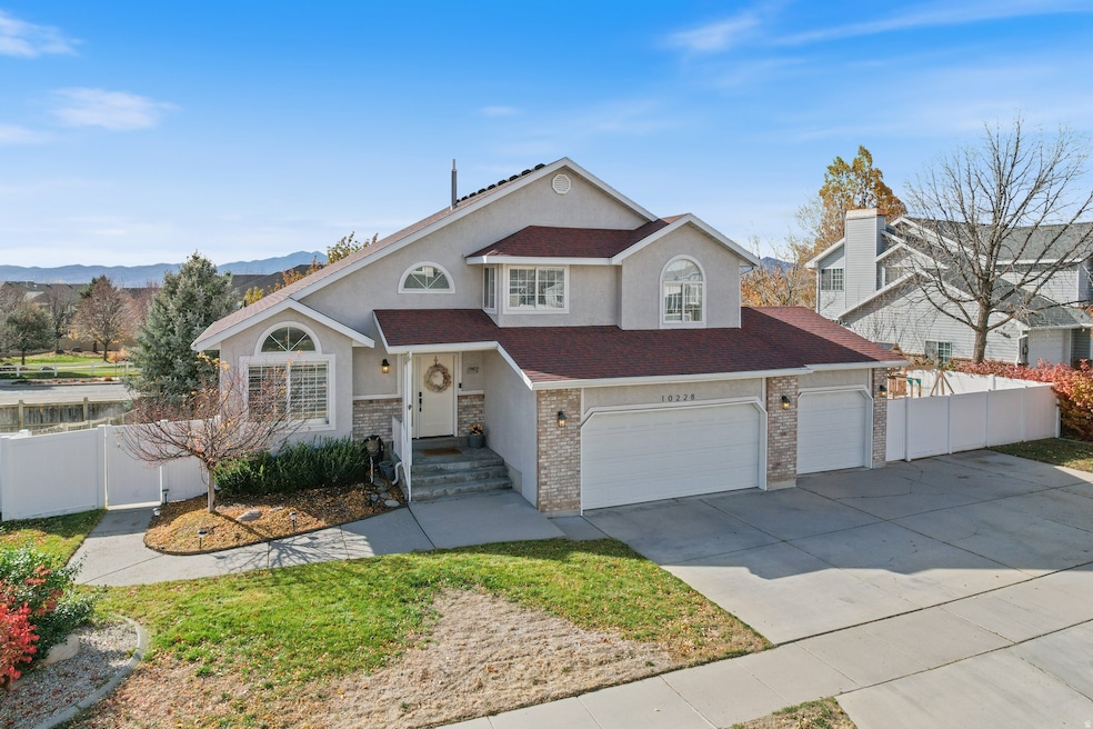 Traditional-style house with concrete driveway, stucco siding, a garage, a shingled roof, and a mountain view