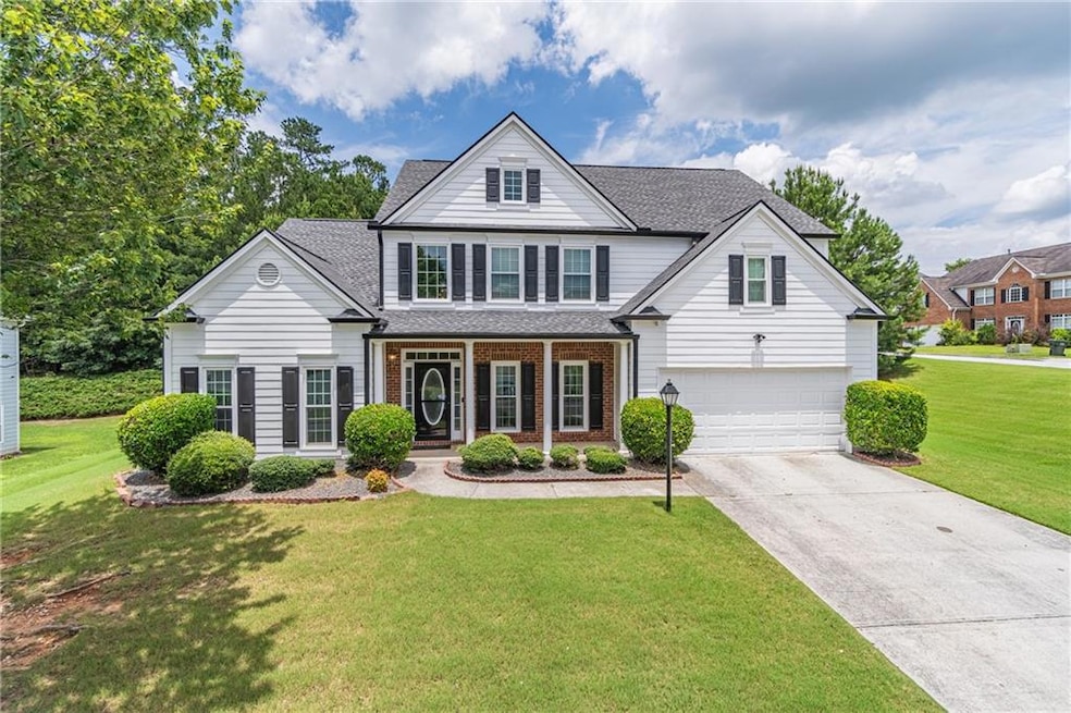 Traditional-style home with a garage, roof with shingles, concrete driveway, a front lawn, and covered porch