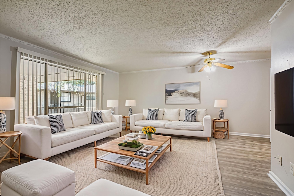 Living area featuring a textured ceiling, wood finished floors, crown molding, and a ceiling fan