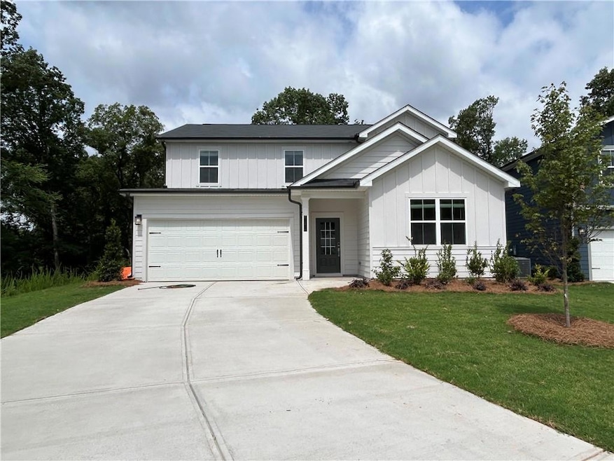 View of front of property with concrete driveway, a garage, a front lawn, and board and batten siding