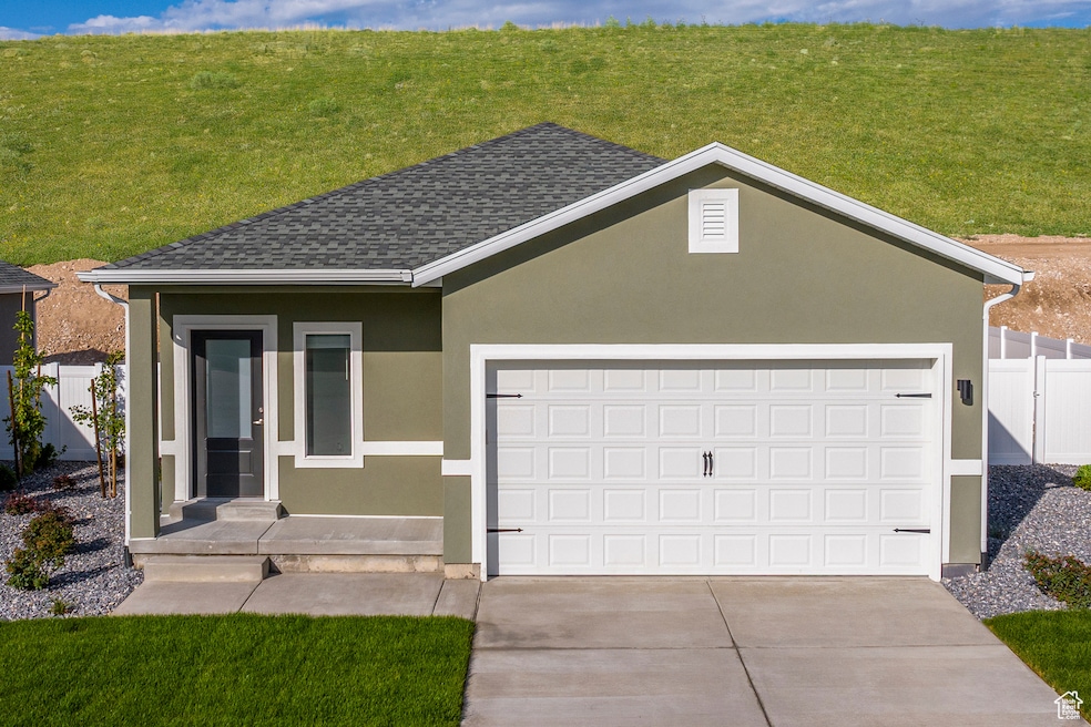 Single story home with a garage, stucco siding, driveway, and roof with shingles
