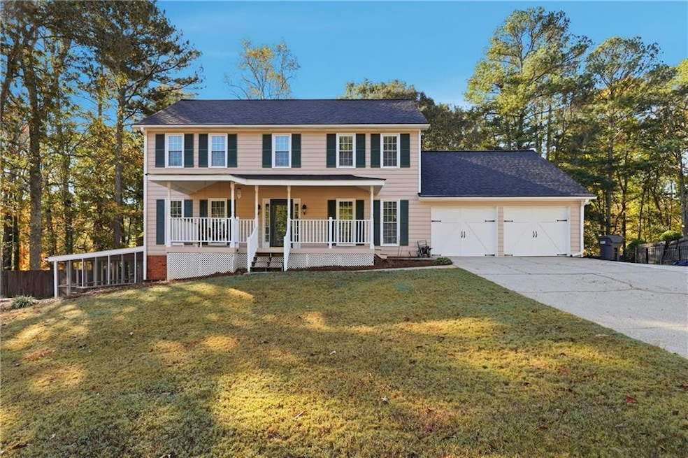 Colonial-style house with a porch, driveway, a garage, and roof with shingles