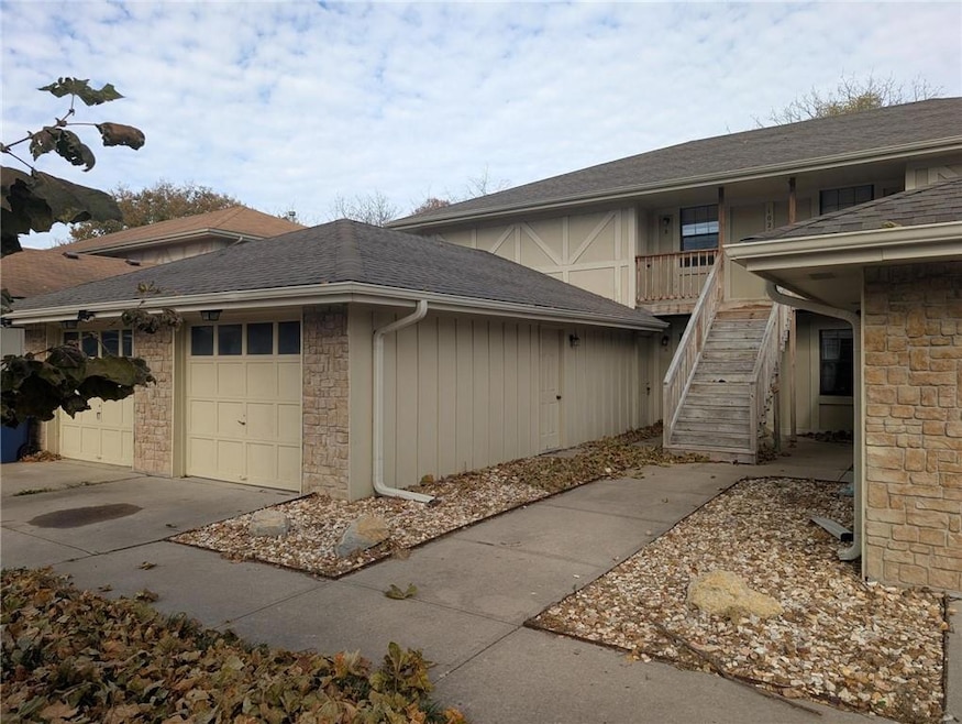 View of property exterior featuring roof with shingles, stairway, and stone siding
