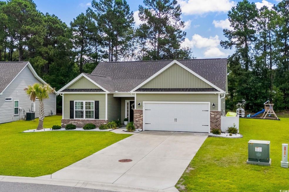 Craftsman-style home with brick siding, a garage, a shingled roof, and a front lawn