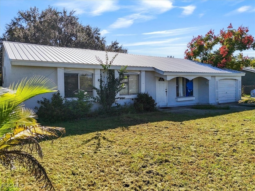Ranch-style house featuring stucco siding, a metal roof, and a front lawn